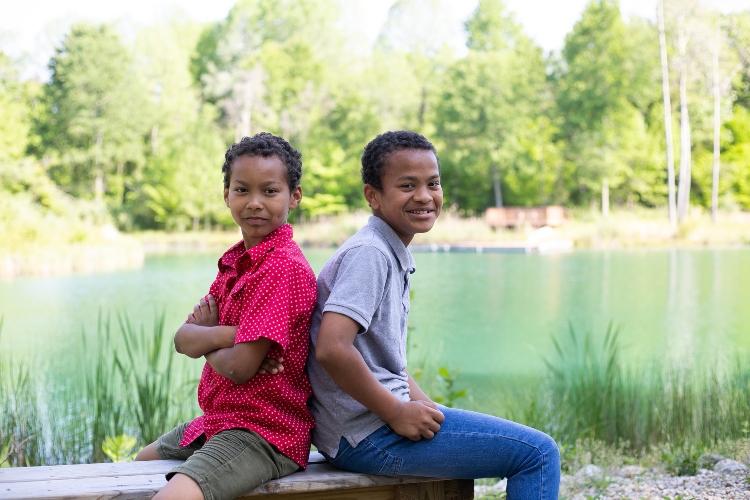 Two boys sitting by a pond