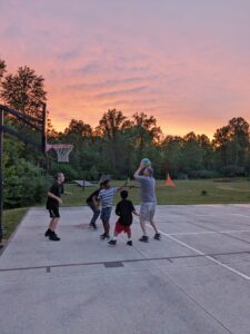 Kids and adult playing basketball outside