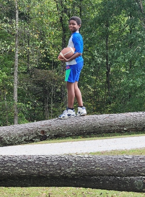 Boy standing on a log with a football