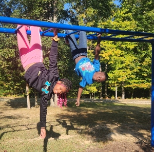 boy and girl hanging upside down on monkey bars